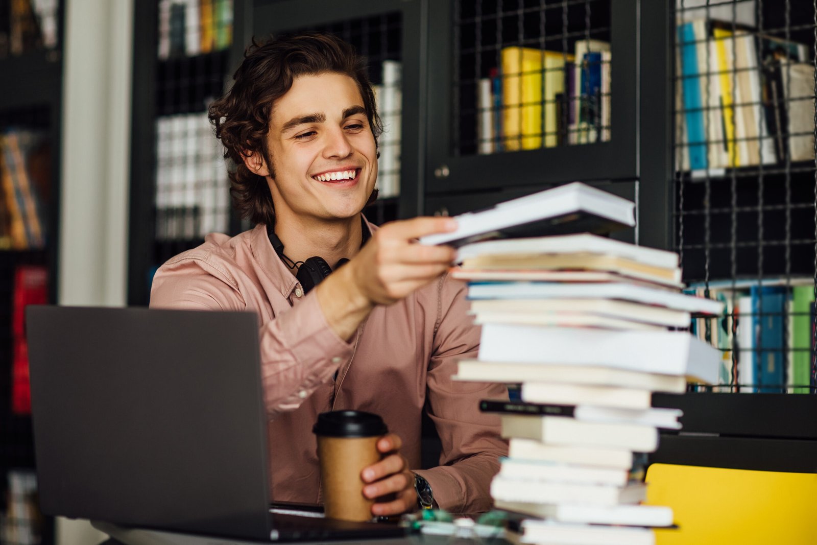 intellectual man reading book sitting library front bookshelves with cup coffee hands